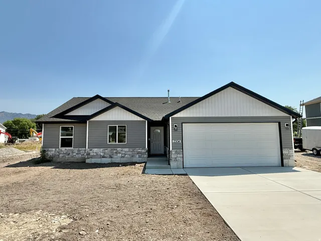 Modern ranch-style home featuring a clean architectural design with peaked rooflines, horizontal siding in neutral gray tones, and a two-car attached garage with white paneled door