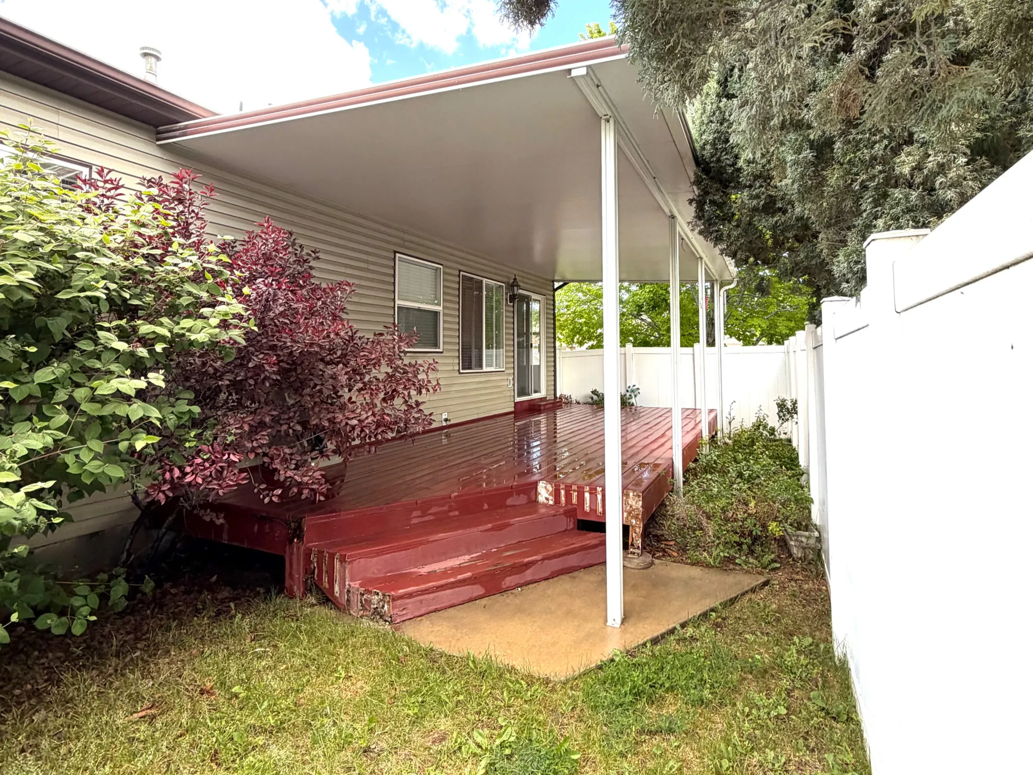 Expansive covered deck featuring a red-stained wood surface and multiple entry points