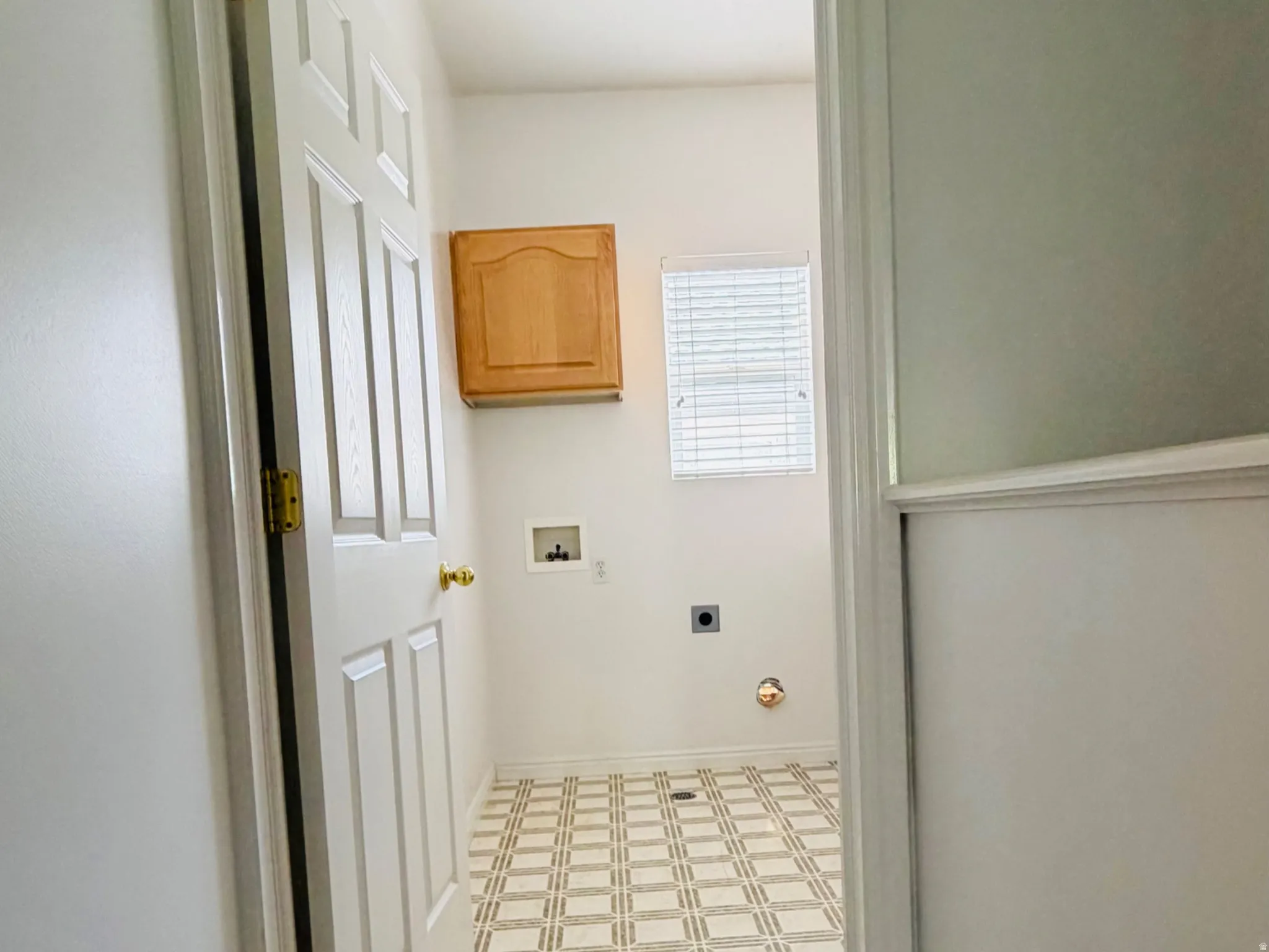 Dedicated laundry room featuring patterned flooring, a window with blinds, and built-in cabinetry