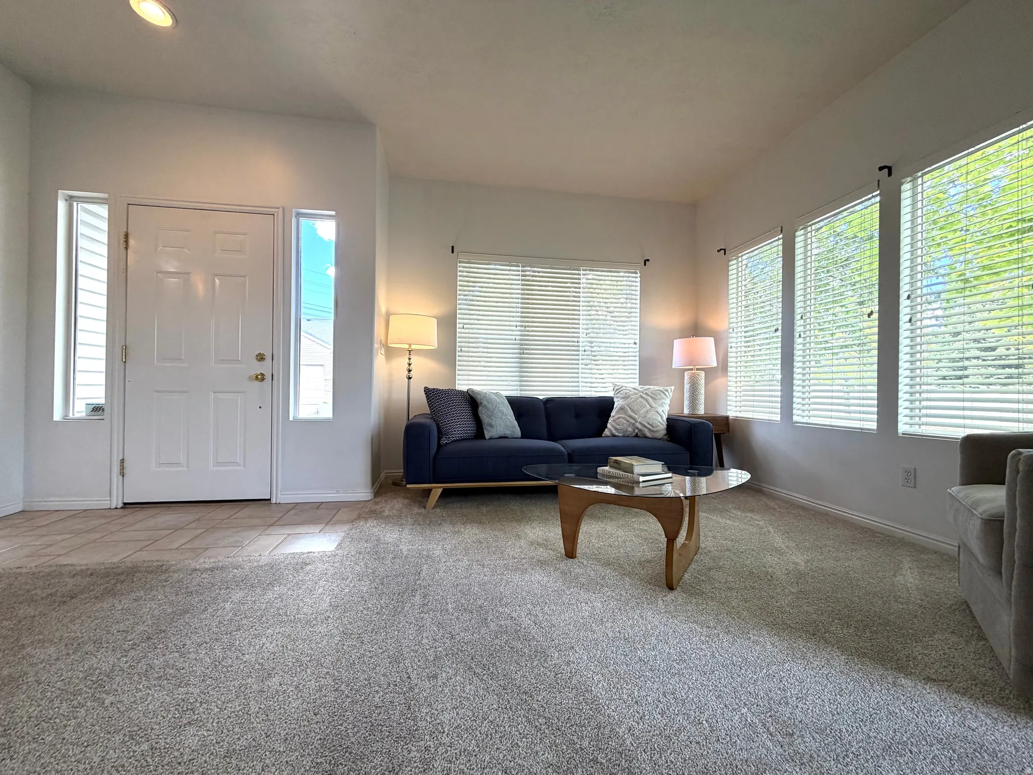 Living area with vaulted ceilings, recessed lighting, and multiple windows with blinds