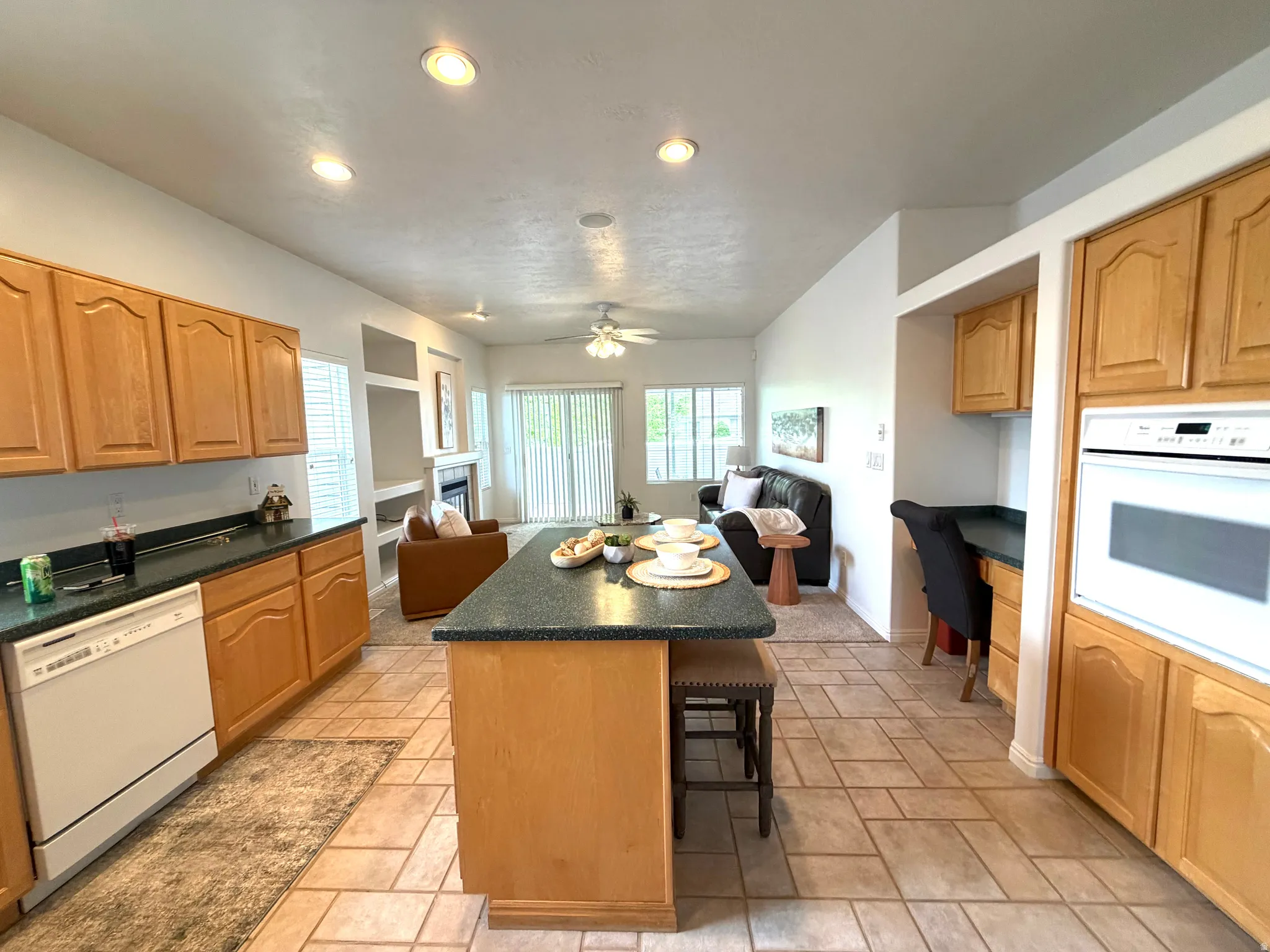 Kitchen with wood cabinetry, integrated wall oven, and a central island with bar seating