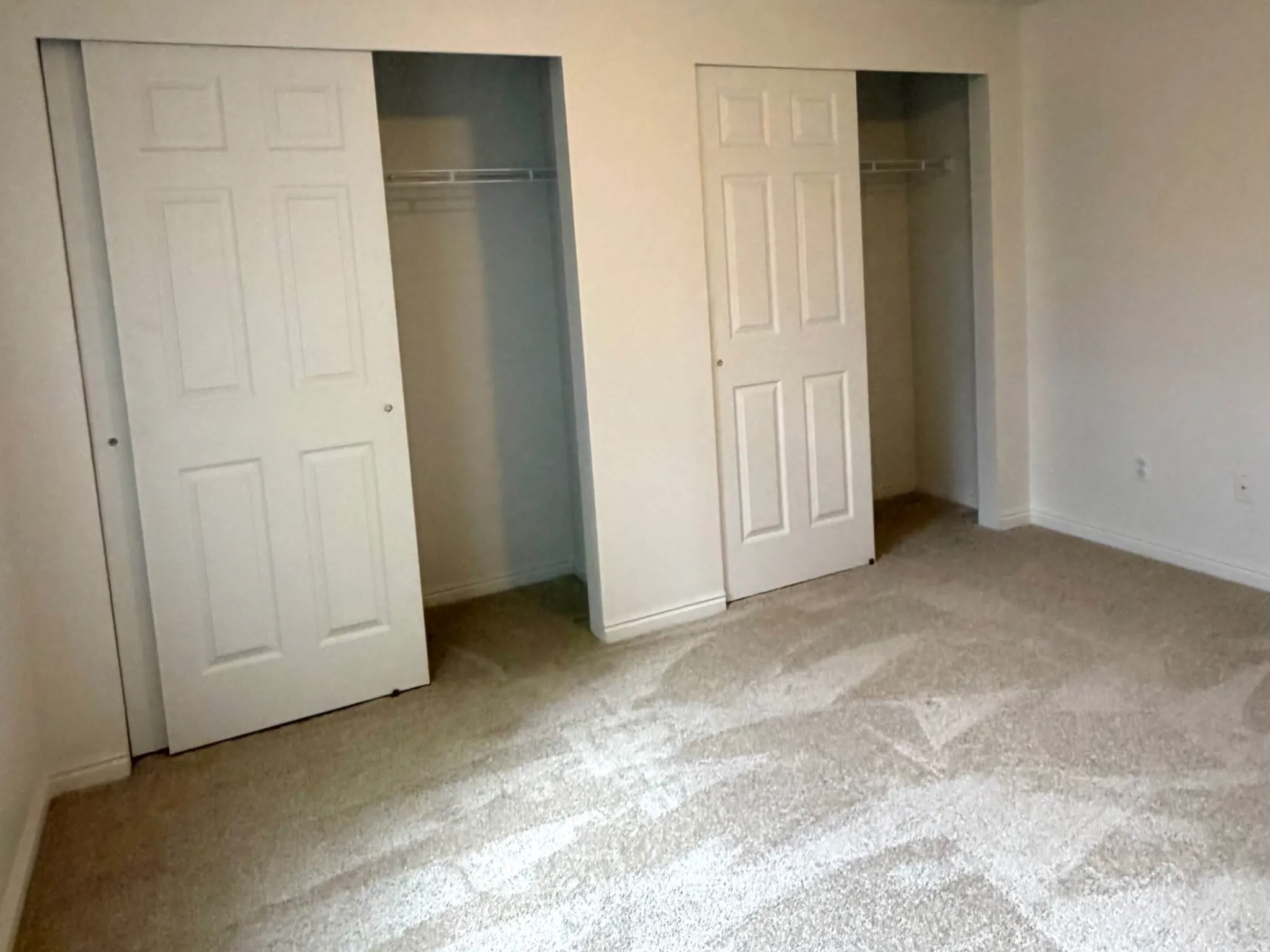 Spacious room featuring light-colored carpeting and white walls