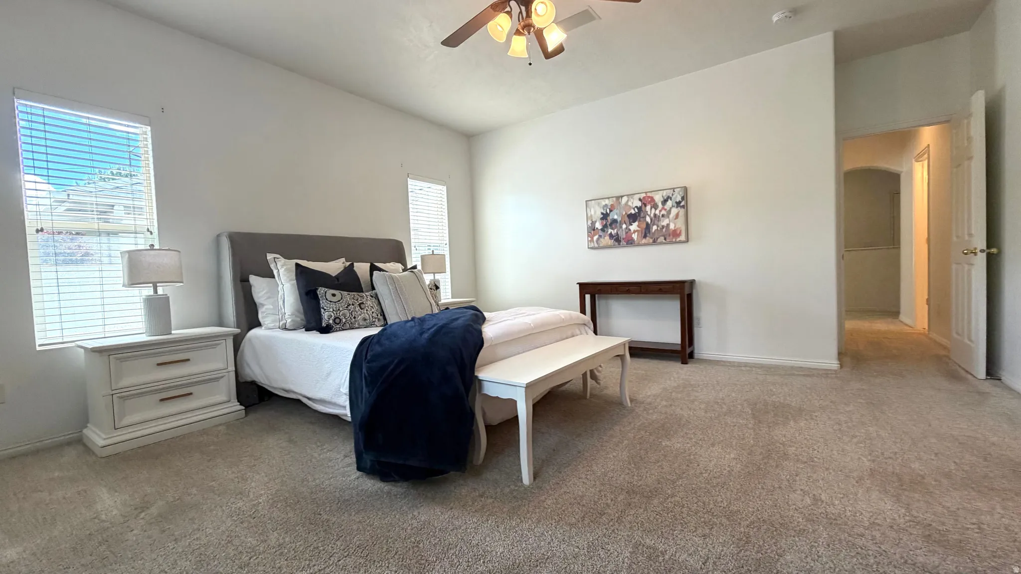 Spacious room featuring neutral carpet flooring, light-toned walls, and multiple windows with blinds