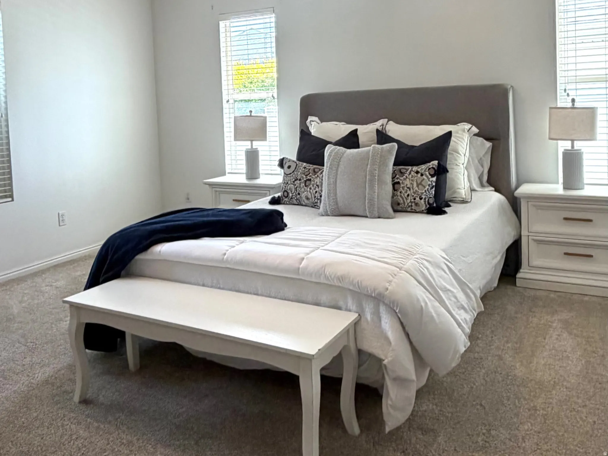 Carpeted room featuring a ceiling fan with integrated lighting, two windows with blinds, and white walls
