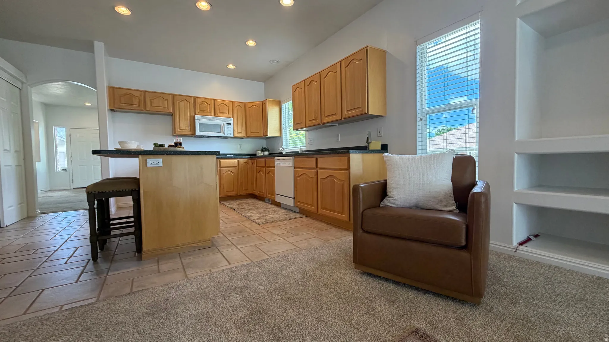 Kitchen featuring wood cabinetry, dark countertops, and integrated appliances