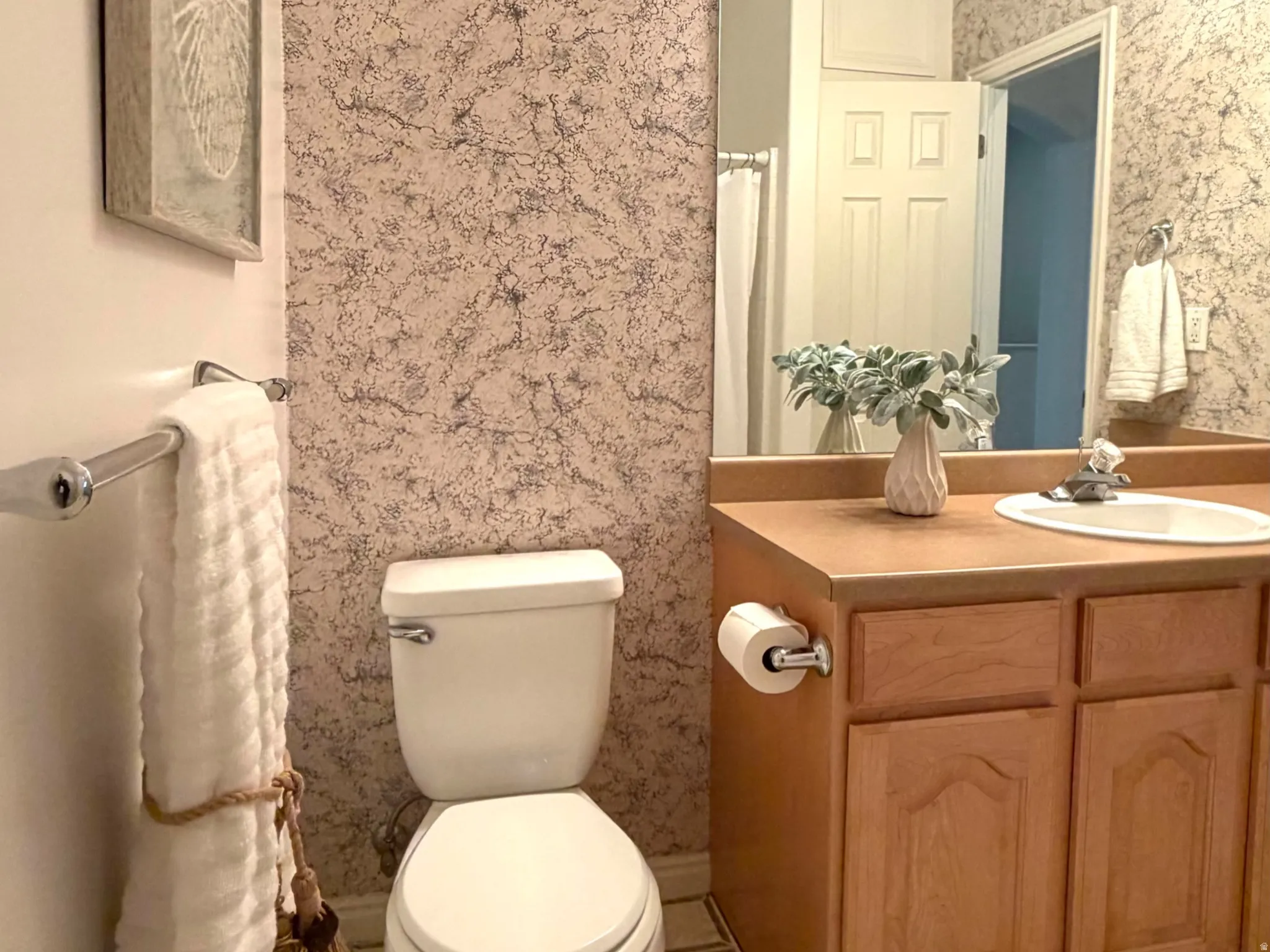 Bathroom featuring a vanity with a laminate countertop, wood-finish cabinetry, and a mirrored wall