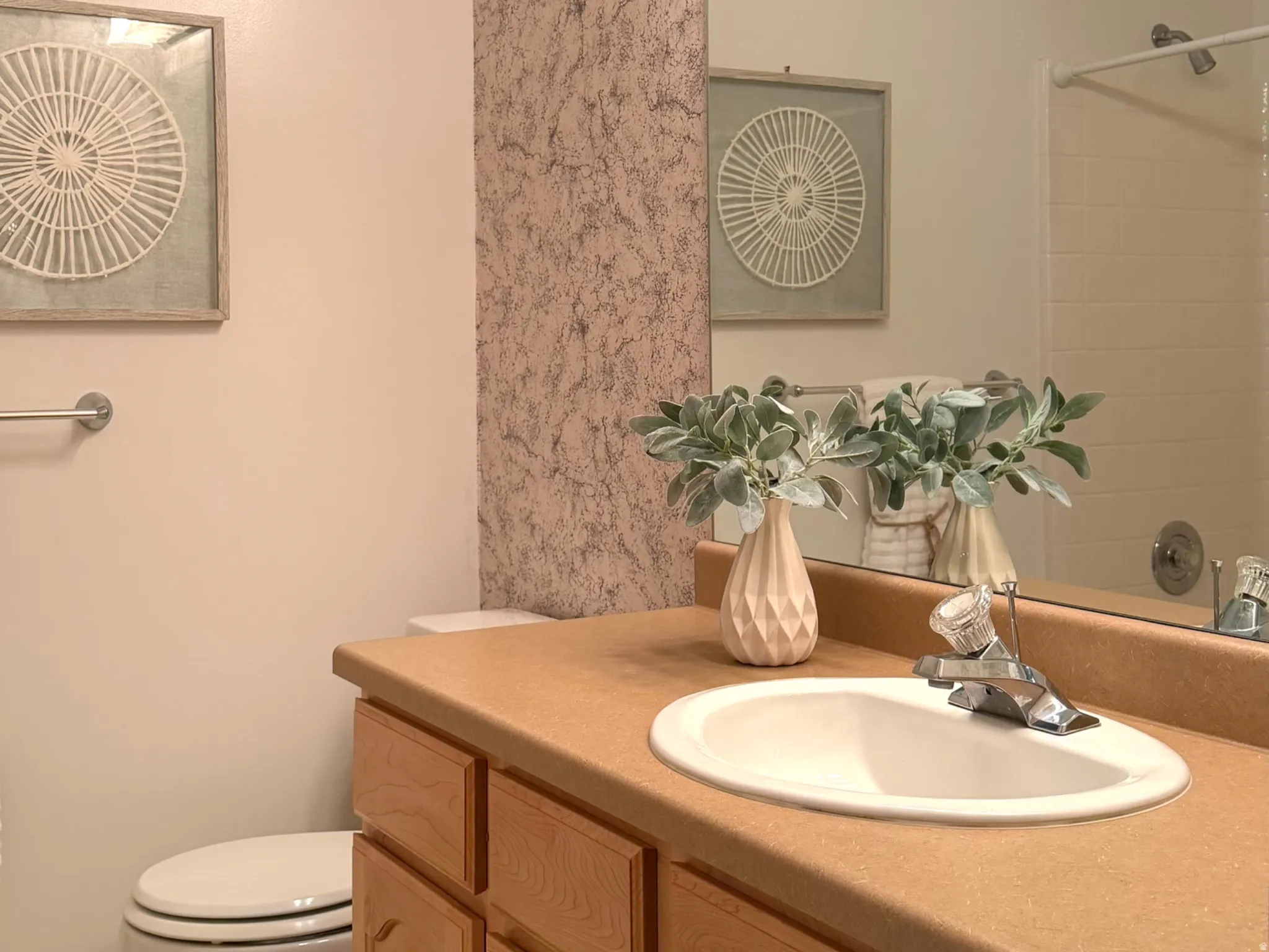 Bathroom featuring a vanity with light wood cabinetry, a tan countertop, and an integrated white sink