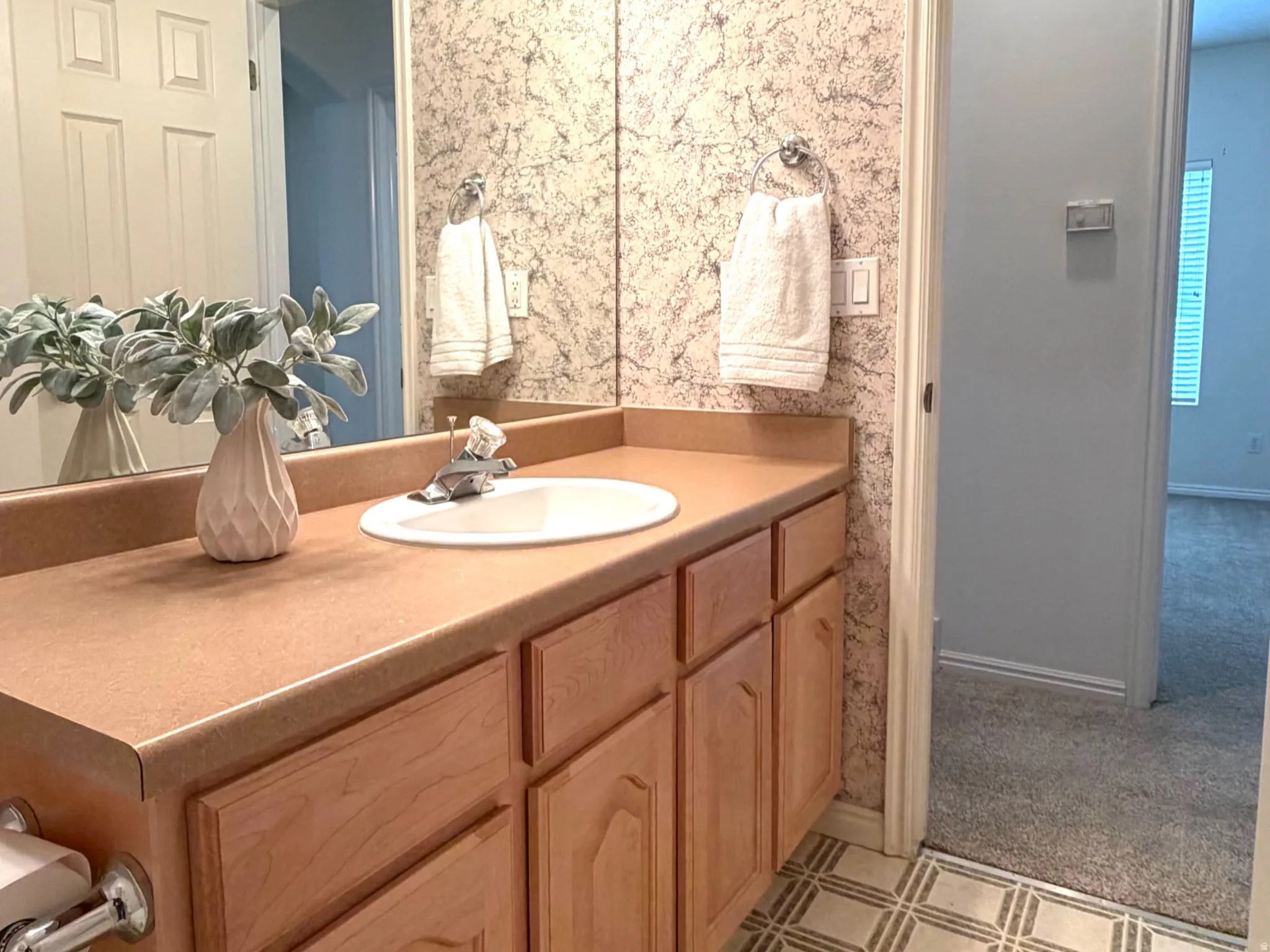 Bathroom featuring a light-toned vanity with an integrated sink and ample storage