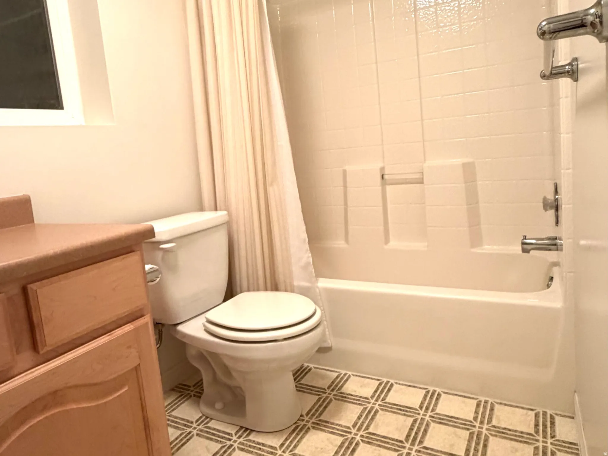 Full bathroom featuring a shower-over-tub combination with white subway tile surround, a single-pane window, and a wood-finish vanity with a countertop