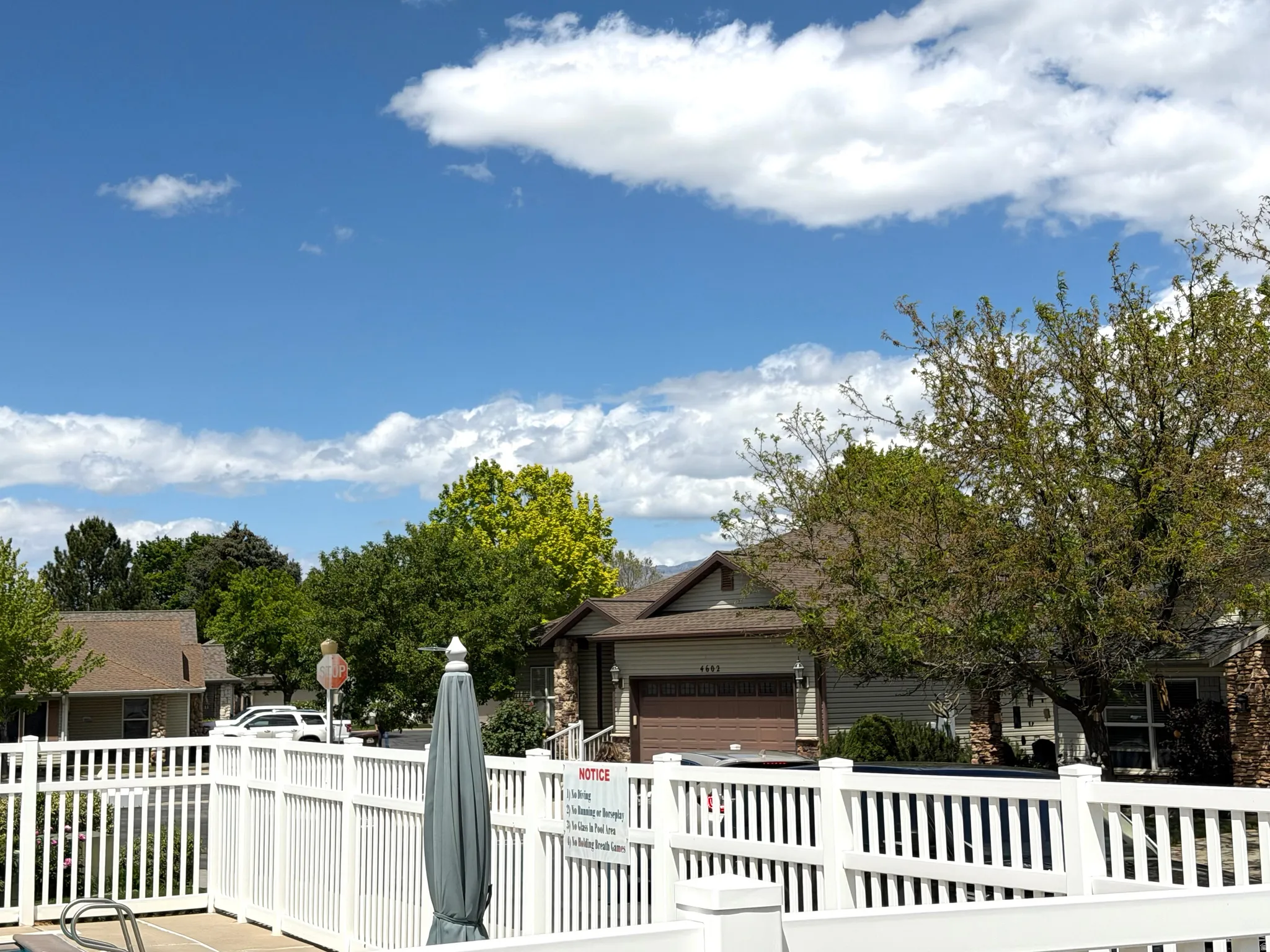 White picket fence enclosure with Subject home behind it.