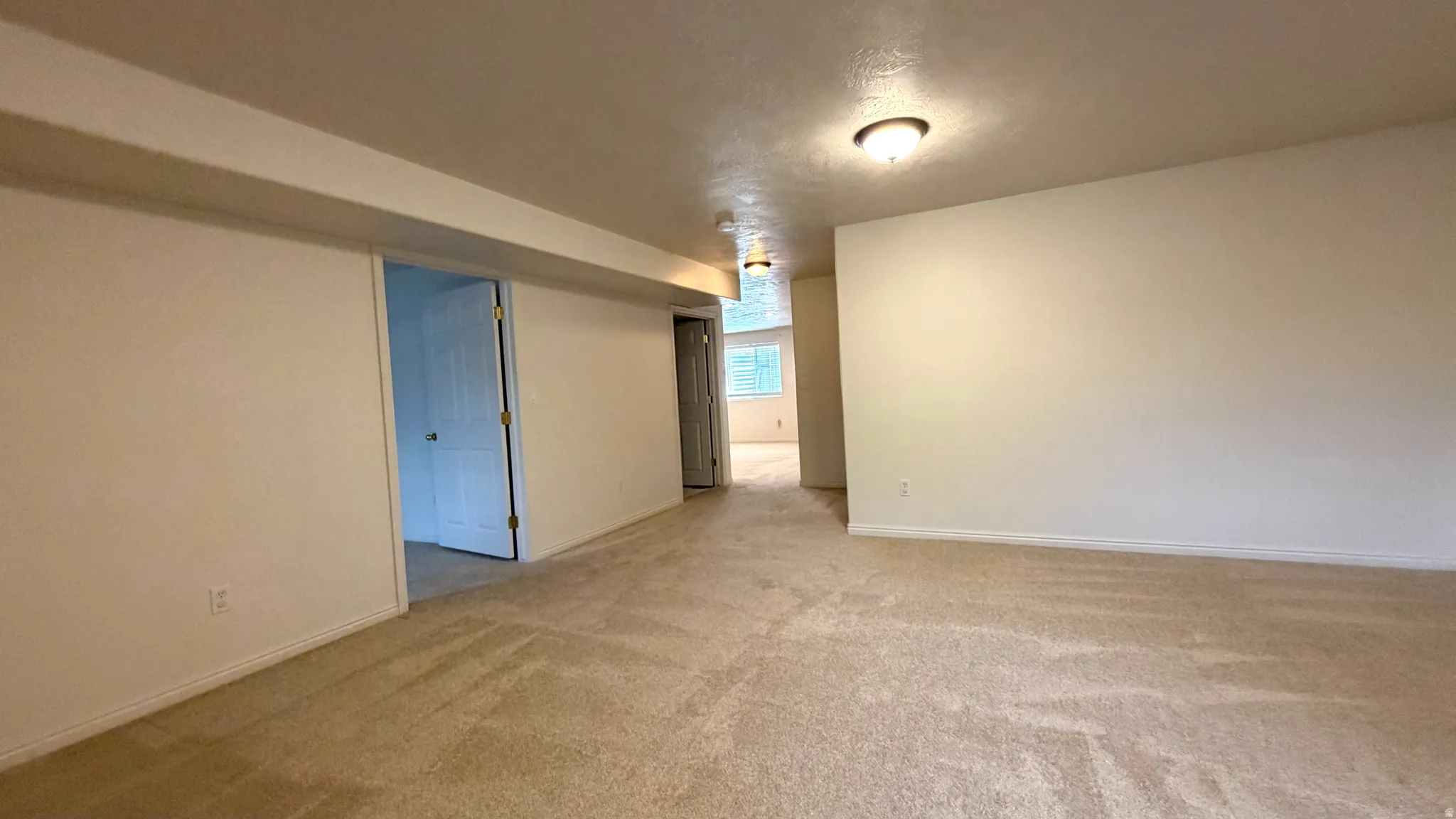 Spacious room with neutral carpet flooring and light-toned walls