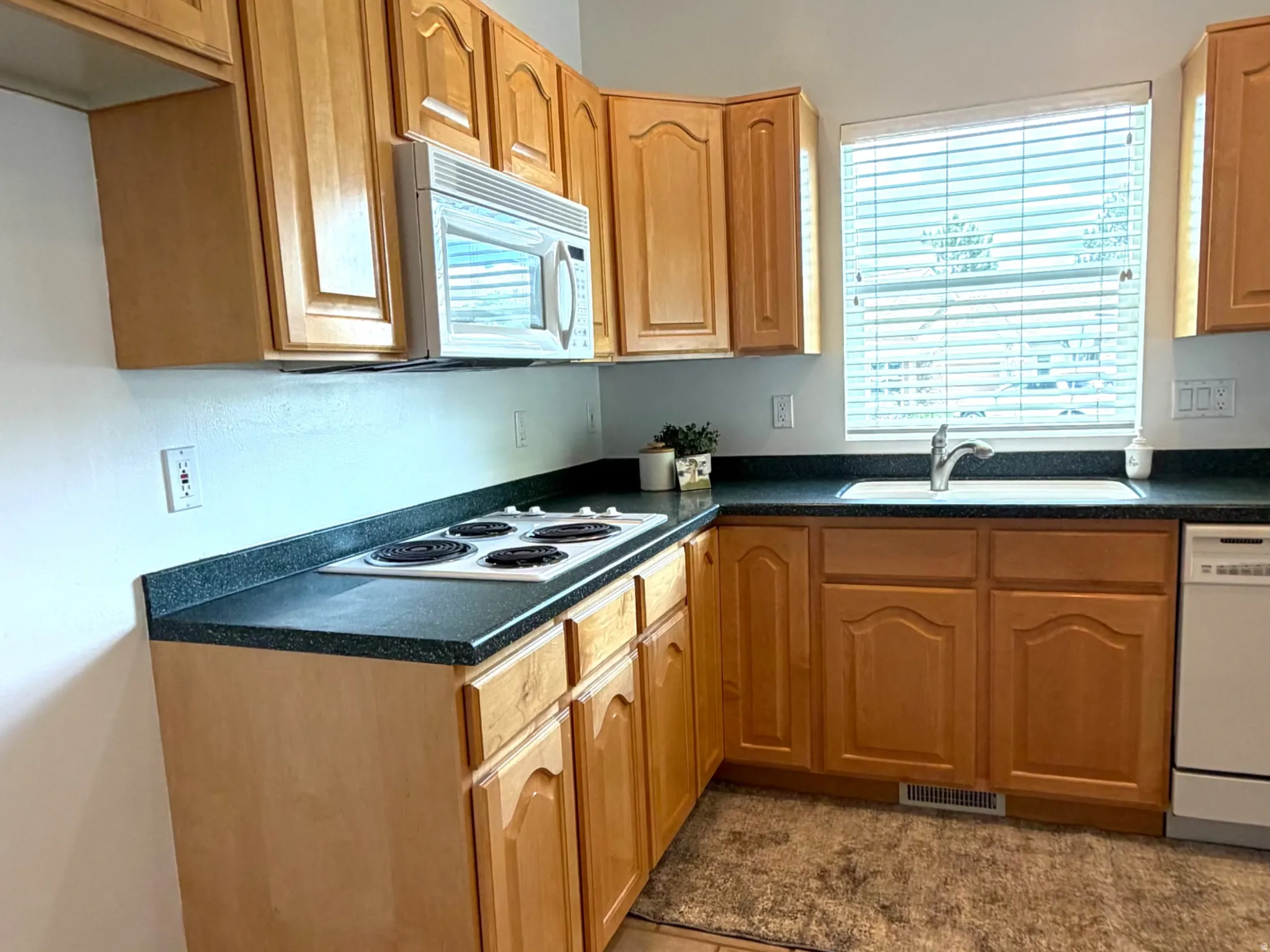 Kitchen featuring light wood cabinetry, dark countertops, and a built-in microwave