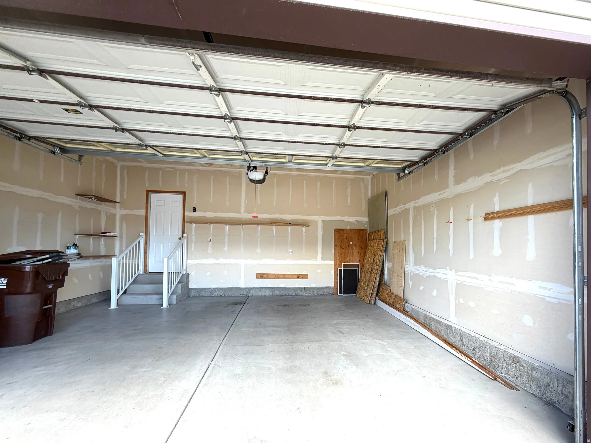 Spacious garage featuring a concrete floor, an overhead garage door, interior access door, and painted drywall walls