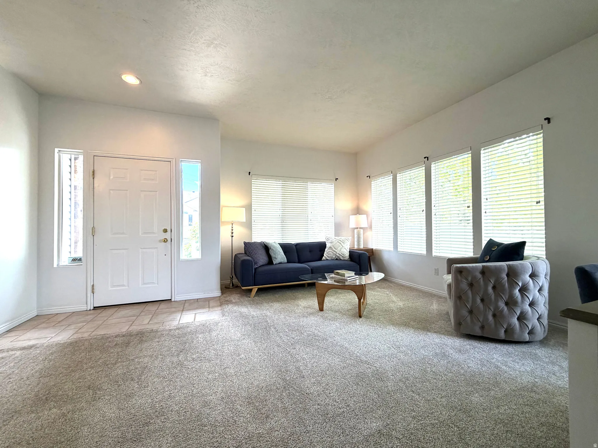 Spacious entry and living area featuring white walls, light-toned carpeting, and a tiled entry