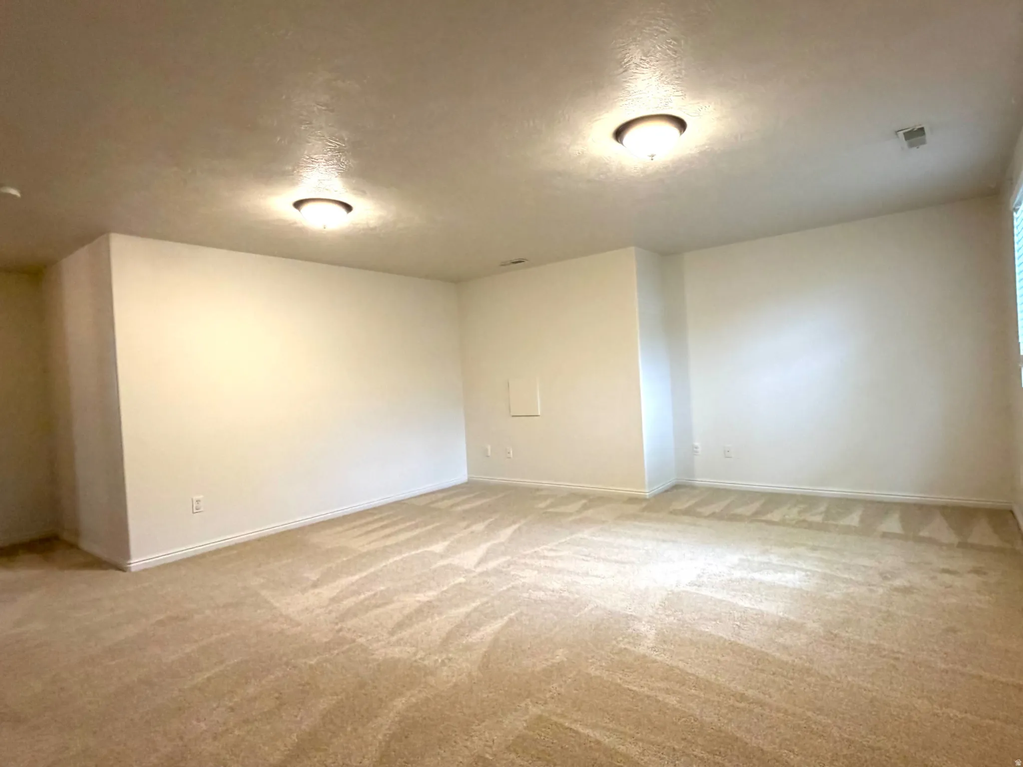 Spacious room featuring neutral carpeting, light-colored walls, recessed lighting, and a window with blinds