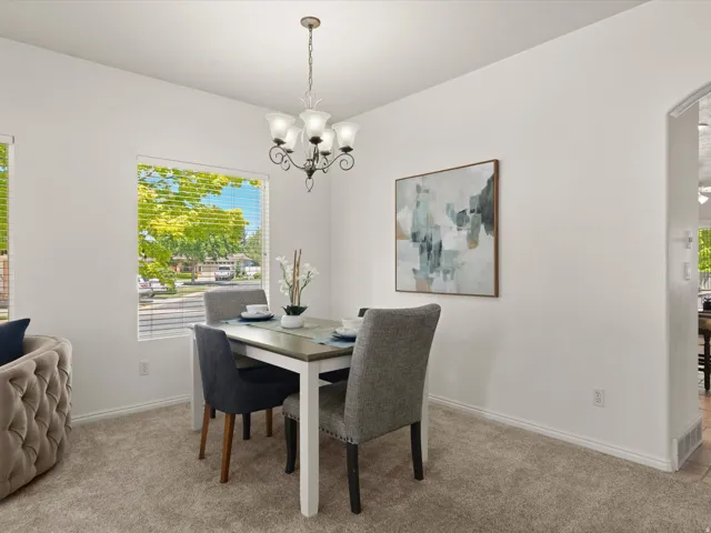 Dining space featuring a multi-bulb chandelier, light neutral-toned carpeting, and white baseboards