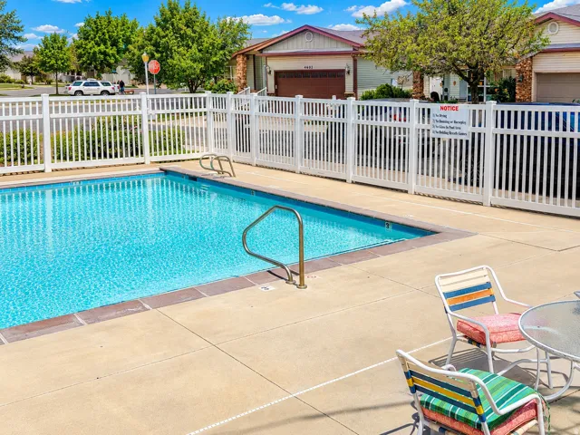 Sparkling outdoor pool featuring a concrete surround, white picket fencing, and stainless steel handrails