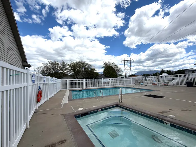 Outdoor aquatic area featuring a swimming pool, separate spa, and surrounding concrete decking