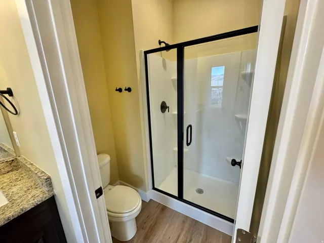 Walk-in shower featuring a sliding glass door with black trim, a built-in shelf, and a black showerhead