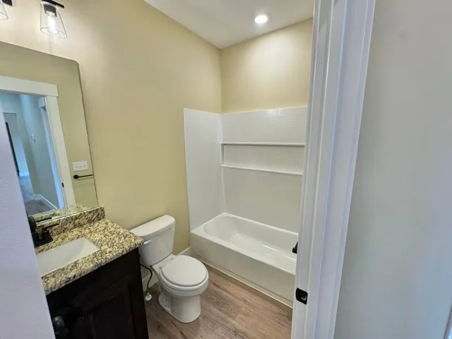 Bathroom featuring a dark wood vanity with a granite countertop, undermount sink, and black hardware