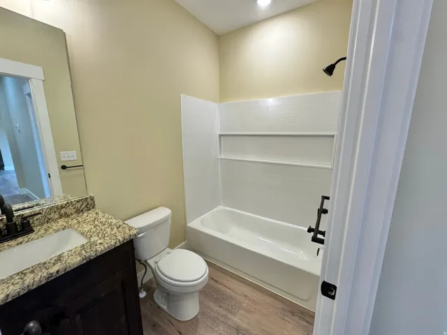 Bathroom featuring a dark wood-finish vanity with an undermount sink, granite-style countertop, and matte black fixtures