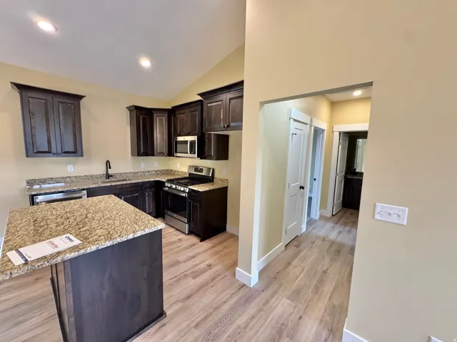 Contemporary kitchen featuring dark wood cabinetry, granite countertops, and stainless steel appliances