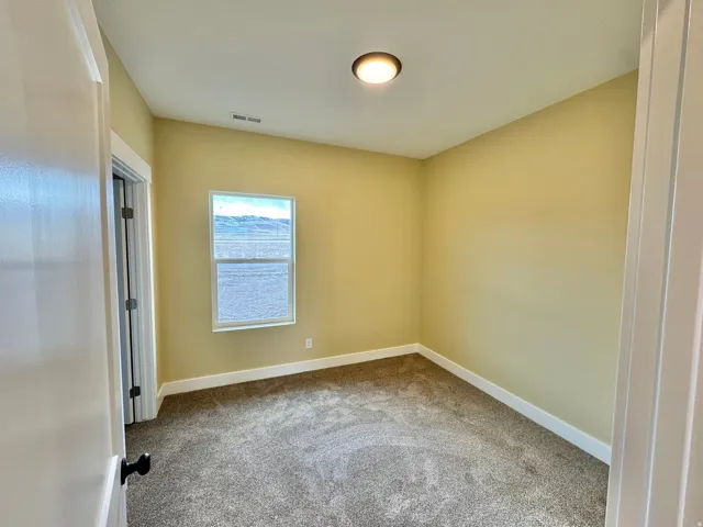 Carpeted room with a single window and a ceiling-mounted light fixture