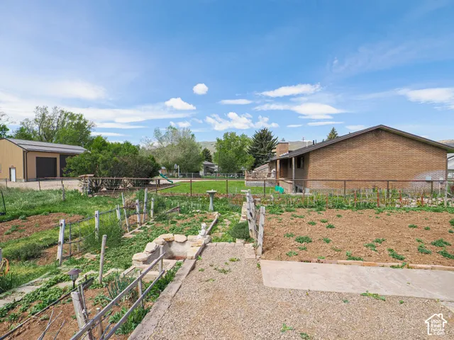 Expansive backyard featuring multiple garden beds, a concrete patio, and a gravel pad