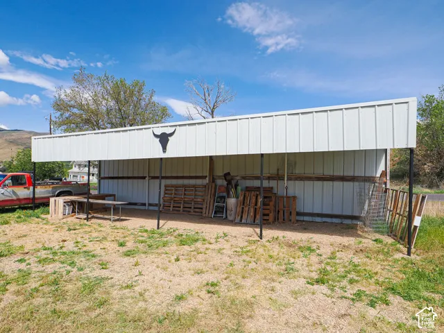 Open-sided metal shed featuring a peaked roof and a gravel floor