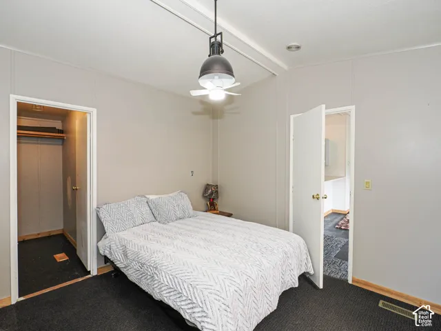 Carpeted room featuring a ceiling-mounted light fixture with fan, light gray wall paneling, and an adjacent closet with wood-finish flooring