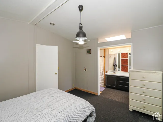 Interior room featuring a ceiling fan with integrated lighting, a white door, and gray paneled walls