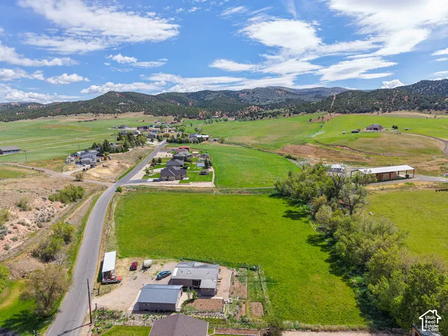 Expansive green acreage featuring a residential structure with a light grey exterior and dark grey roof
