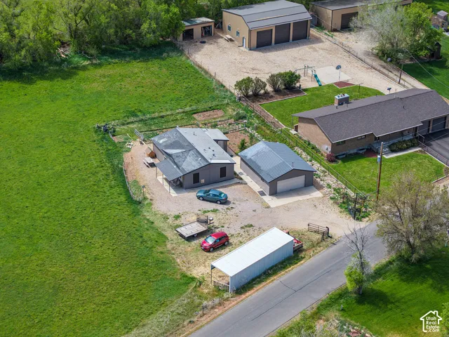 Expansive property featuring multiple structures including a main residence, a detached two-car garage, a large three-door workshop, and an additional storage shed