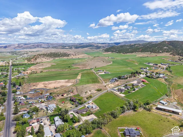 Expansive rural landscape featuring scattered residential properties, green fields, and distant mountainous terrain