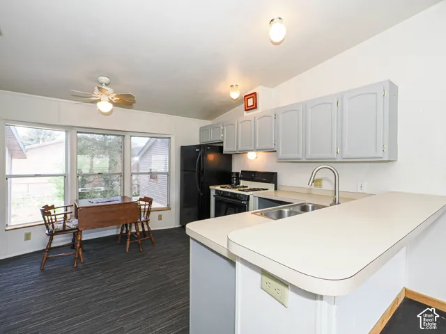 Kitchen featuring light gray cabinetry, a double basin stainless steel sink, and a breakfast bar