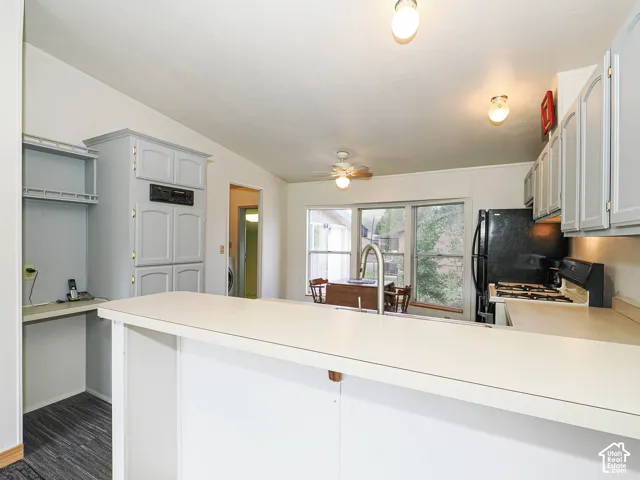 Open kitchen area featuring a breakfast bar, light gray cabinetry, and a black refrigerator