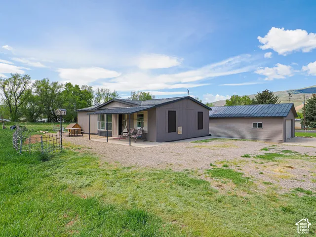 Single-story residence featuring a covered front porch and a detached garage with a metal roof