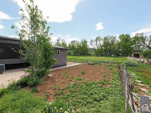 Landscaped outdoor area featuring garden beds, a stone pathway, and a rustic wooden fence