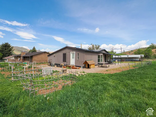 Expansive backyard featuring a large green space, fenced garden beds, and an extended gravel patio
