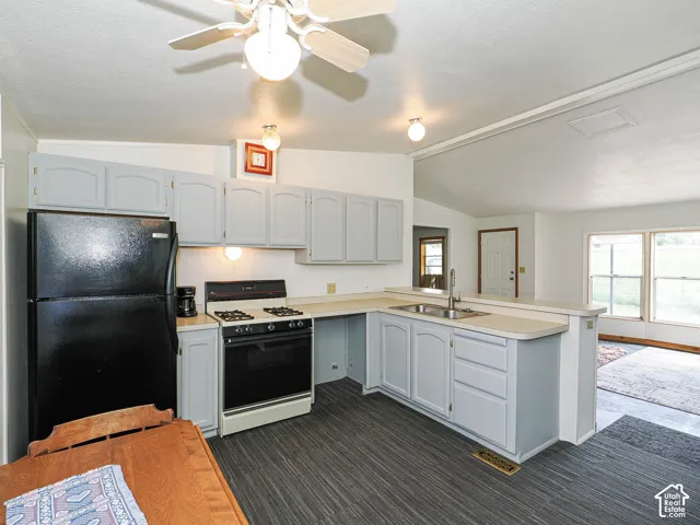 Kitchen featuring extensive light gray cabinetry, laminate countertops, a gas range, a double basin stainless steel sink with a high-arc faucet, and wood-finish flooring