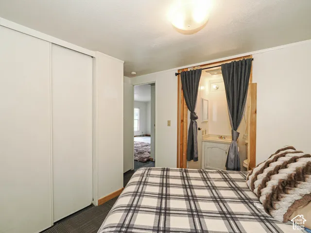 White interior walls featuring a closet with sliding doors, a ceiling-mounted light fixture, and dark gray carpet flooring