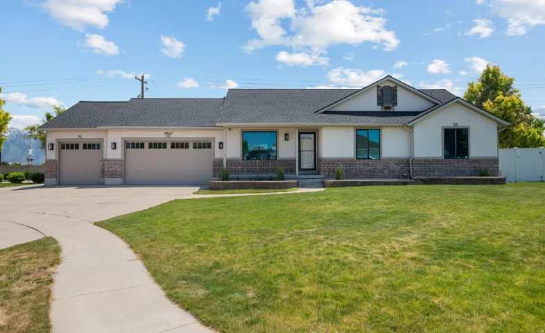 Ranch-style exterior featuring a dark asphalt shingle roof, light stucco siding, and a stone veneer foundation