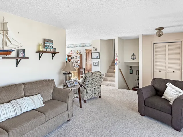 Spacious living area featuring light-toned carpeting and neutral wall tones