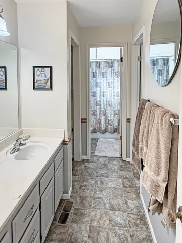 Bathroom vanity featuring a single basin sink, chrome faucet, and ample storage cabinetry