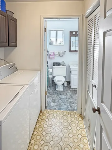 Dedicated laundry area with upper cabinetry and a patterned flooring