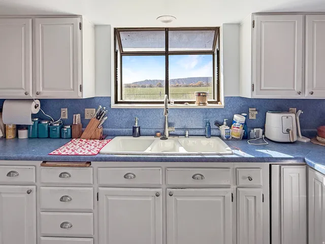 Kitchen featuring white cabinetry, a double basin sink, and a window with a mountain backdrop