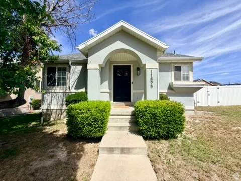 Stucco exterior with a covered entry, featuring a dark front door and an exterior light fixture