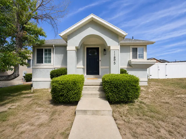 Stucco exterior with an arched entryway and a contrasting dark entry door