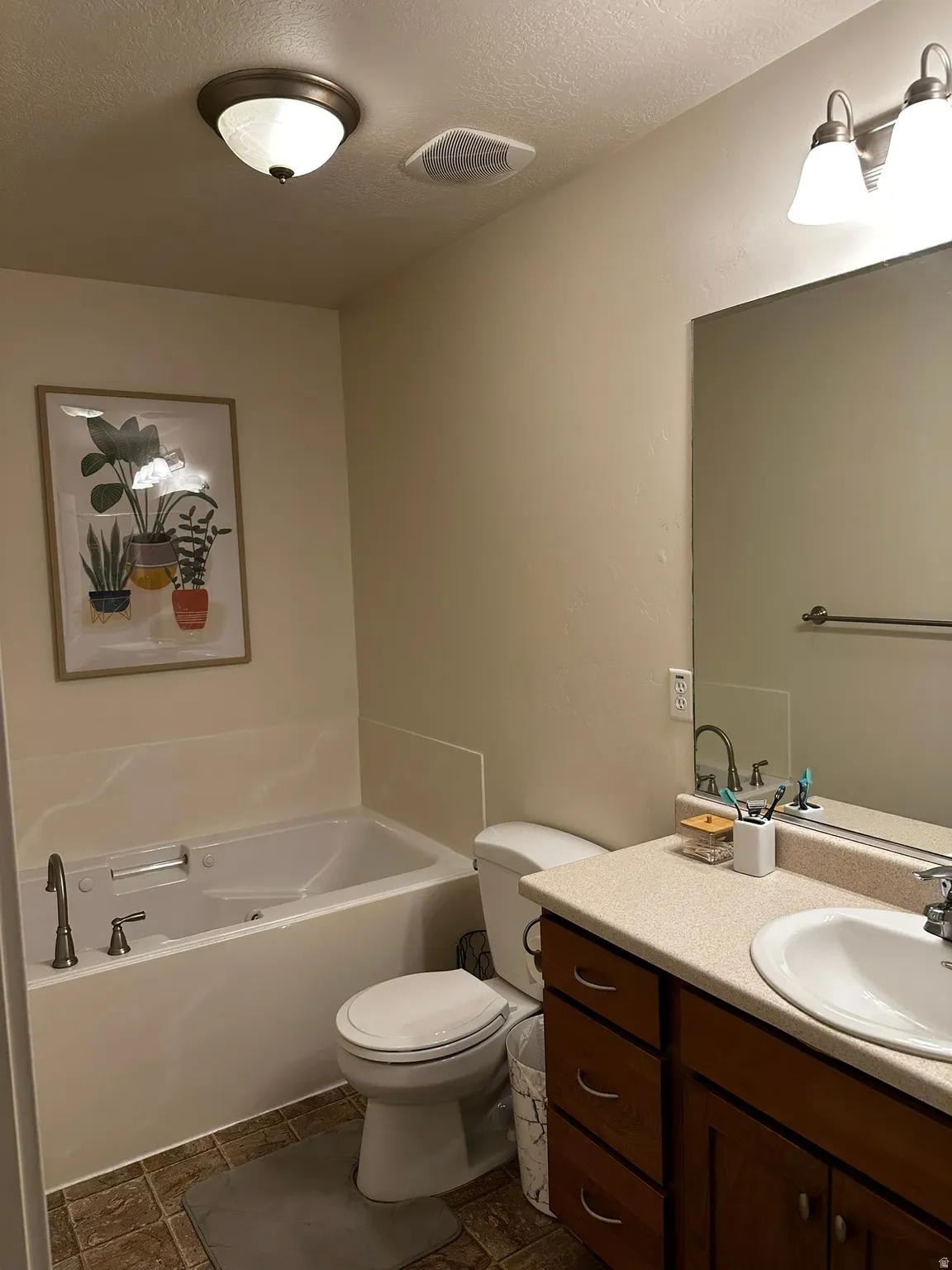Bathroom featuring a white soaking tub, white toilet, and a vanity with a light-colored countertop