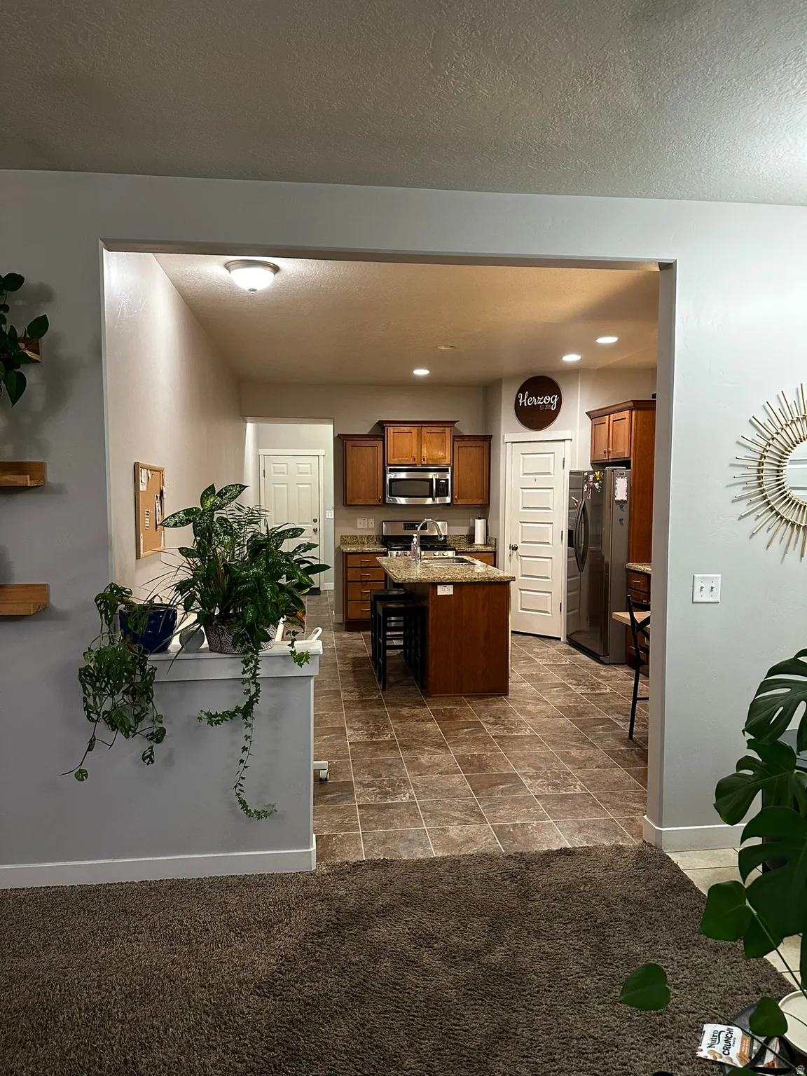 Kitchen featuring wood cabinetry, stainless steel appliances, a center island with bar seating, and tile flooring